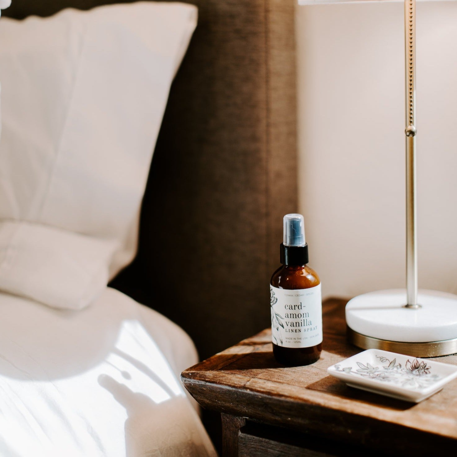 4oz Cardamom Vanilla linen spray on side table next to lamp