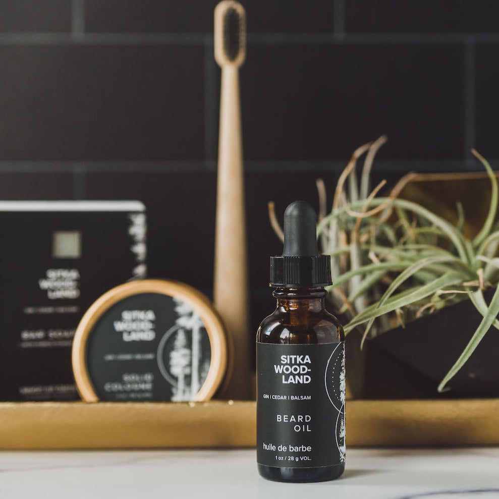 Sitka Woodland beard oil on counter with solid cologne and bar soap in the background