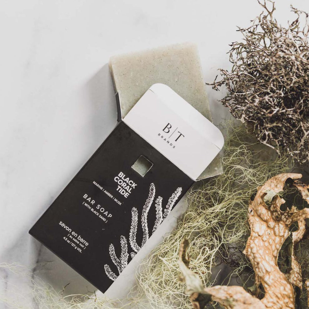 Black Coral Tide bar soap on white table and green foliage