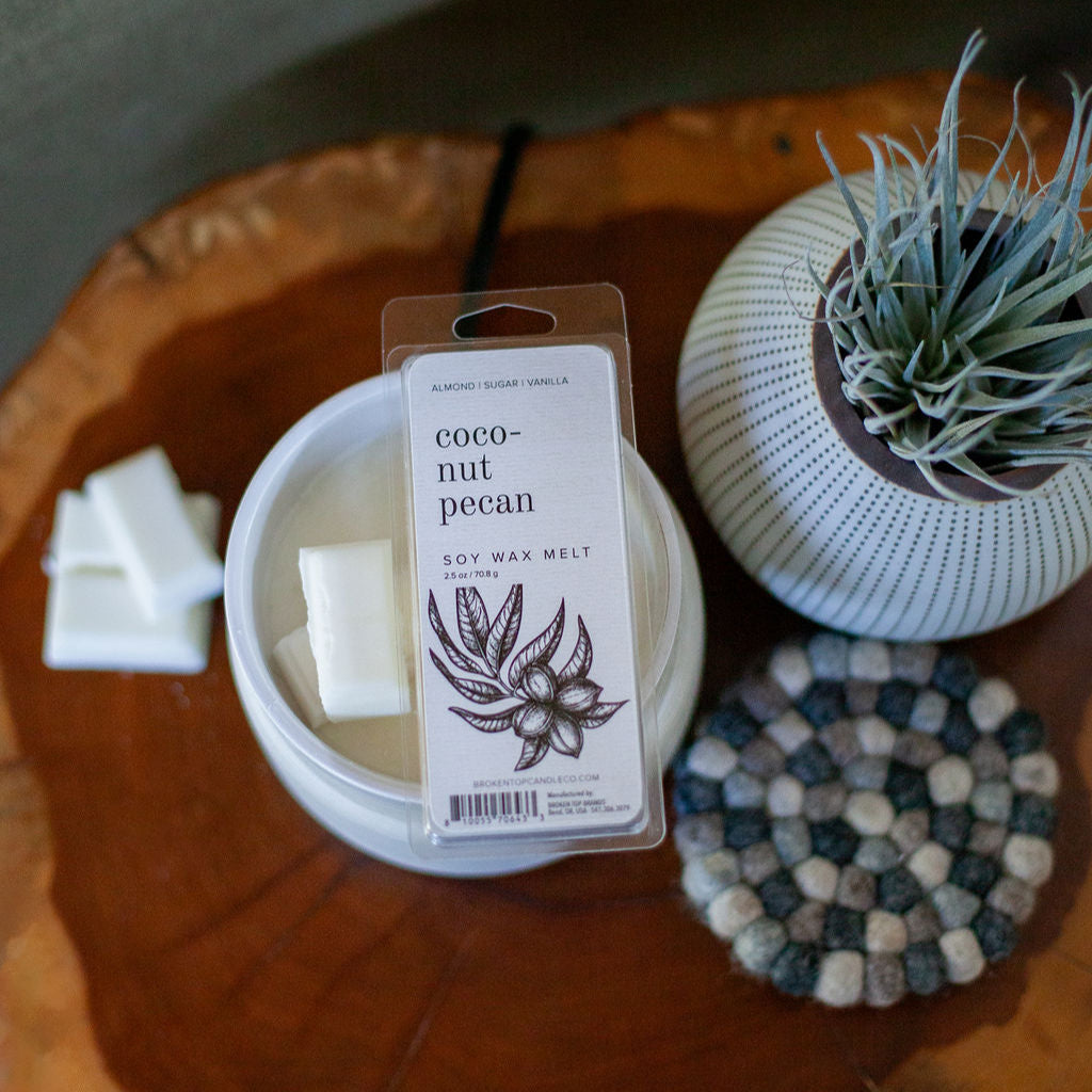 Coconut Pecan Wax Melt on a wooden side table next to a small plant.