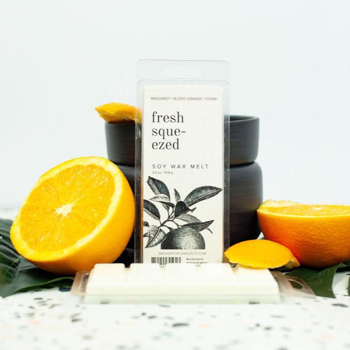 Fresh Squeezed Wax Melts infront of black wax warmer next to leaves and citrus