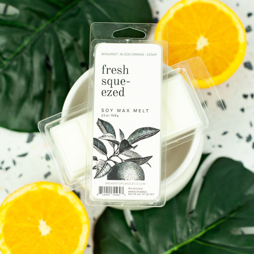 Fresh Squeezed Wax Melts resting on wax warmer next to leaves and citrus