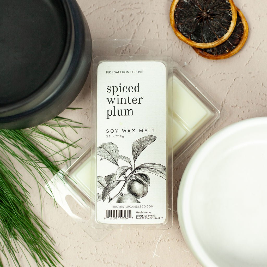 Spiced Winter Plum Wax Melts next to black wax warmer next to pine needles and citrus