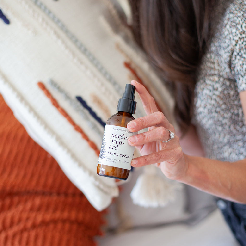 4oz Nordic Orchard Linen Spray being held by a woman's hand.