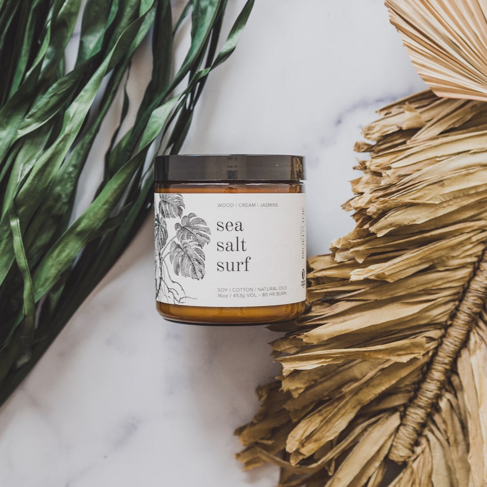 16oz Sea Salt Surf candle on white marble and leaves