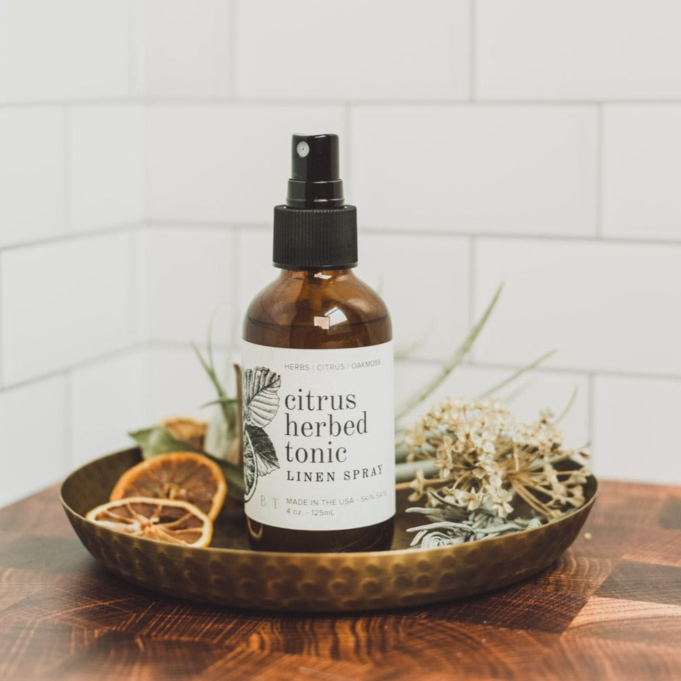 4oz Citrus Herbed Tonic linen spray on metal dish and dried citrus
