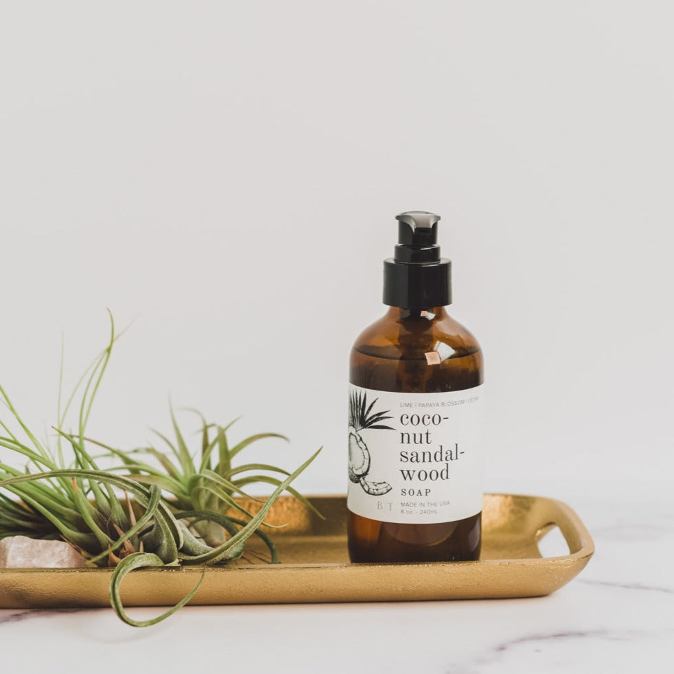 Coconut Sandalwood 8oz liquid soap on metal dish next to greenery