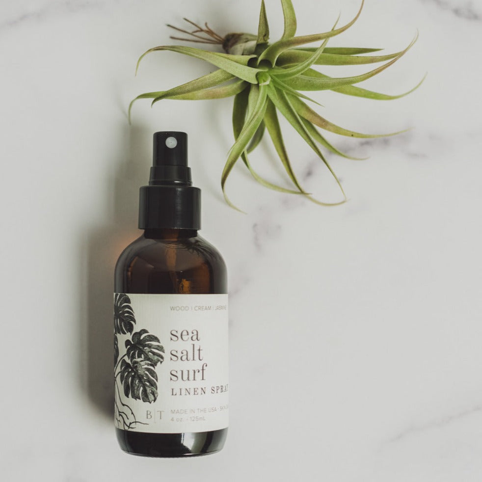 4oz Sea Salt Surf spray on white table near green foliage
