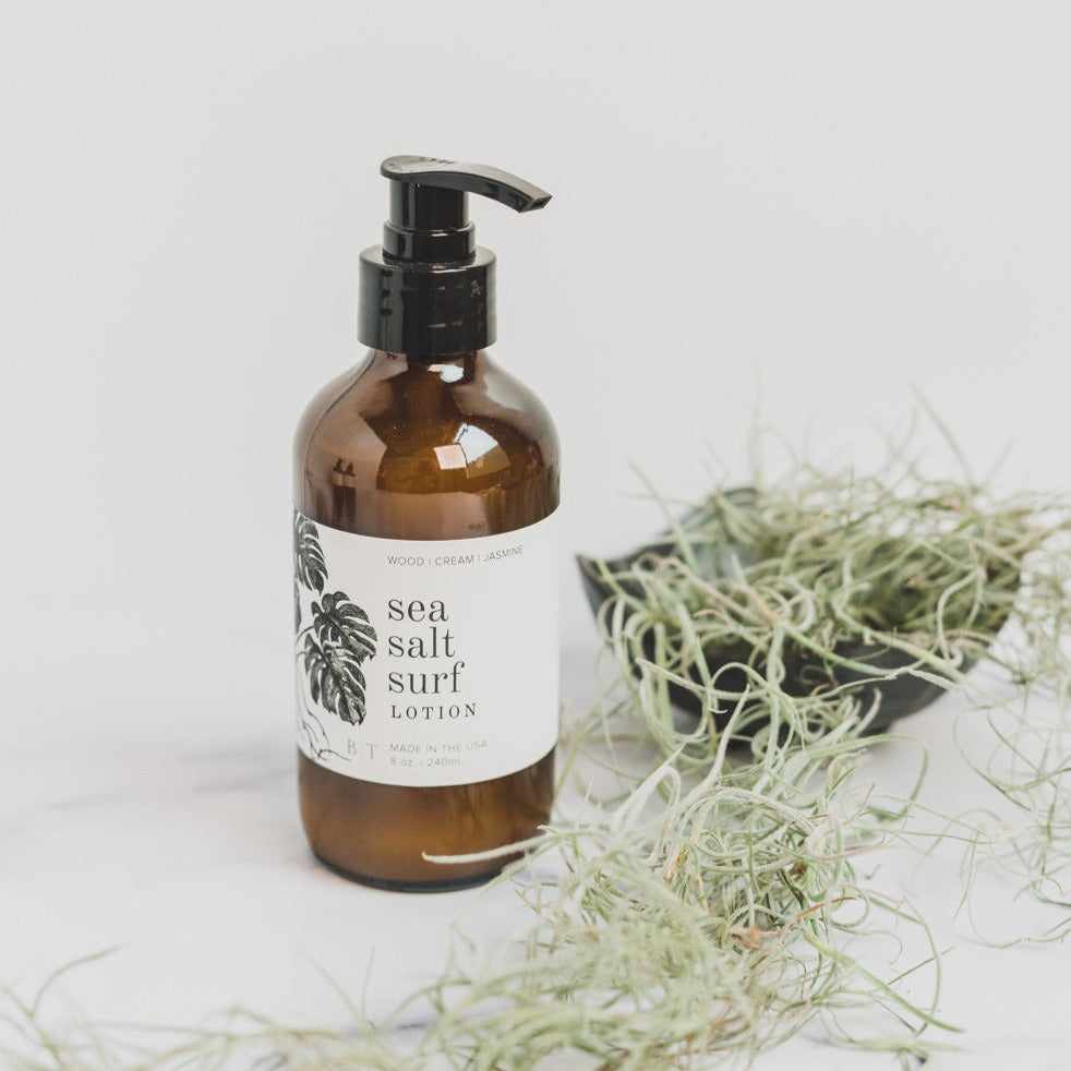 Sea Salt Surf 8oz lotion on white table next to greenery