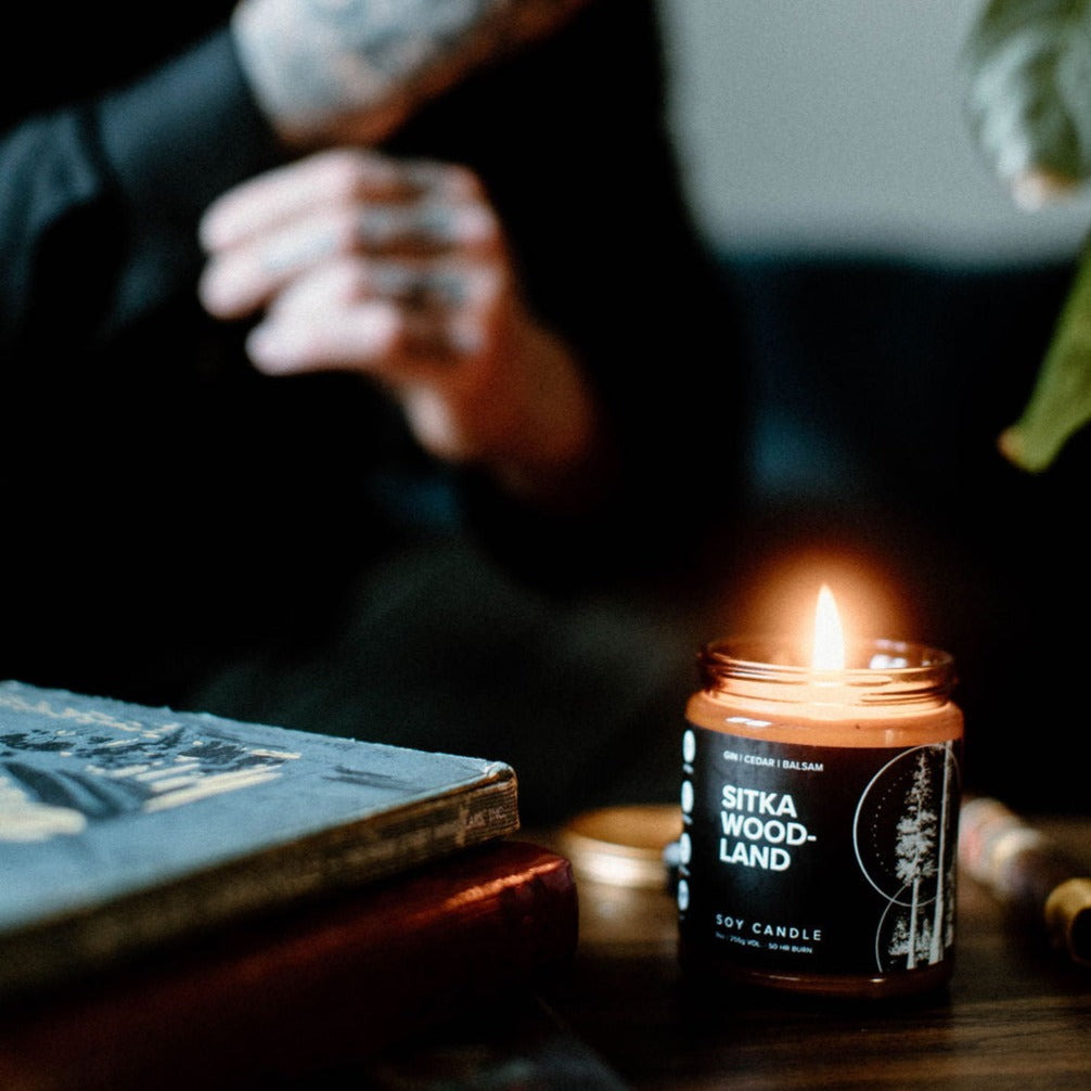 9oz Sitka Woodland candle on table next to man