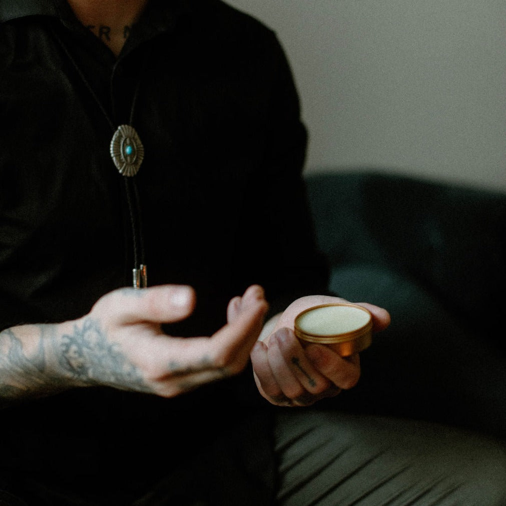 Birch Charcoal solid cologne being held by tattooed gentleman