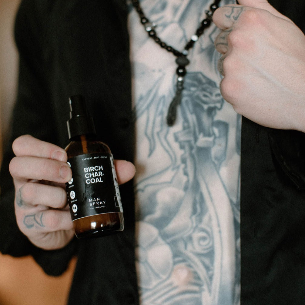 4oz Birch Charcoal linen spray being held by tattooed man