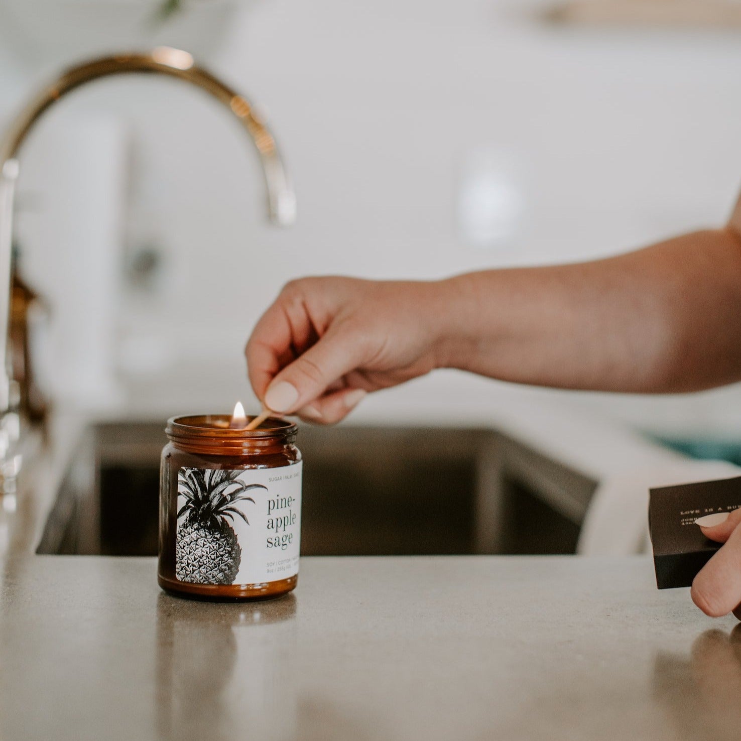 9oz Pineapple Sage candle on kitchen counter and lit by wooden match