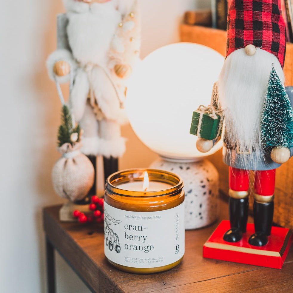 16oz Cranberry Orange candle on wooden table surrounded by holiday decor