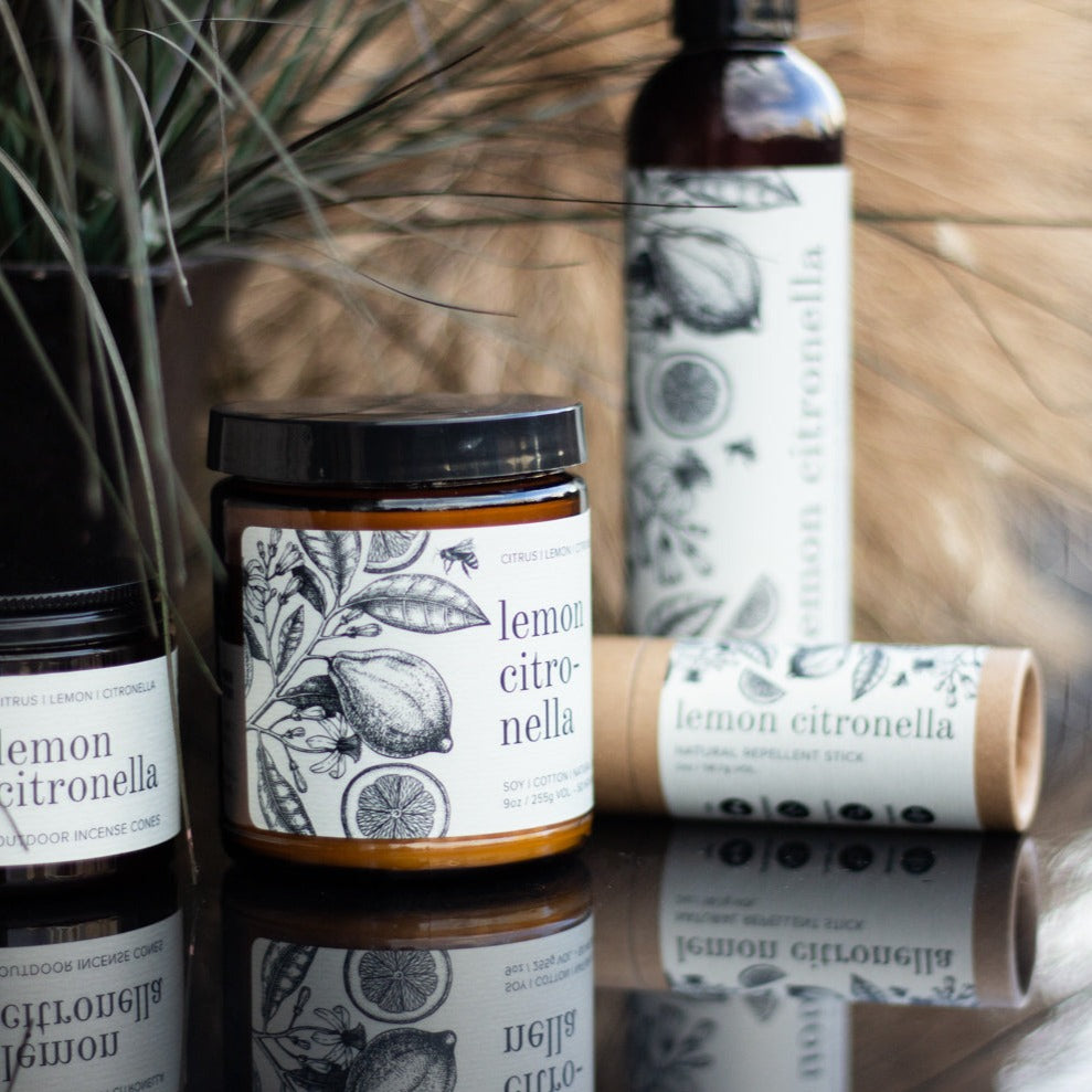 9oz Lemon Citronella candle on black table next to other citronella products