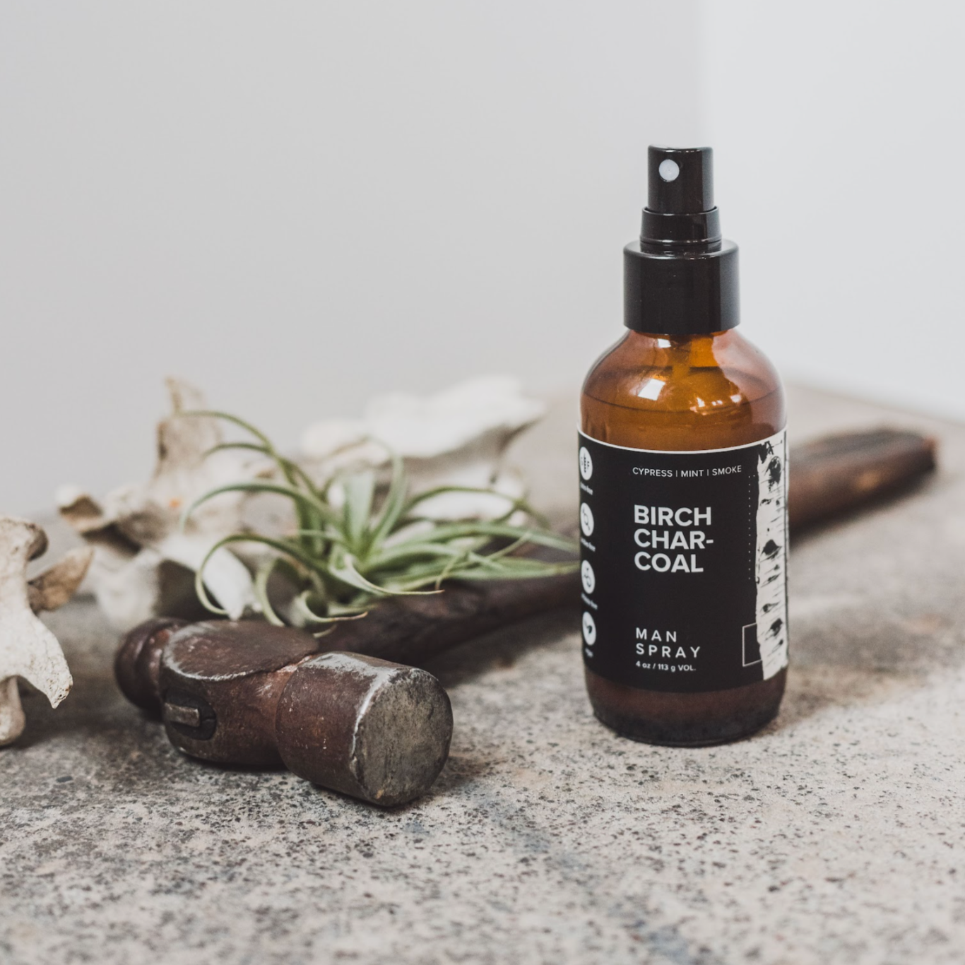 4oz Birch Charcoal linen spray on concrete next to hammer