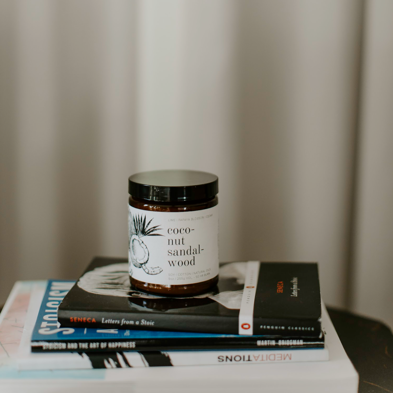 9oz Coconut Sandalwood candle on 3 books