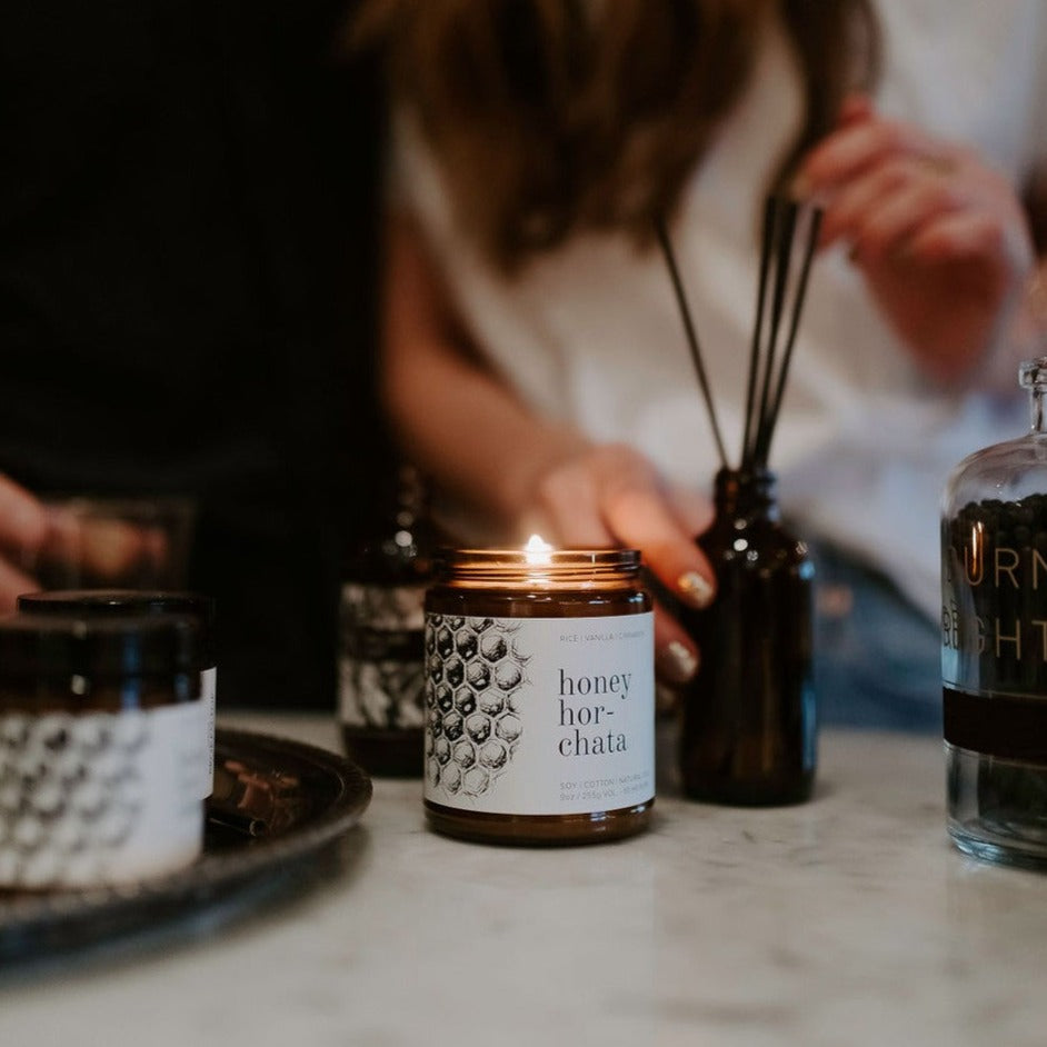 9oz Honey Horchata candle on counter next to reed diffuser and women