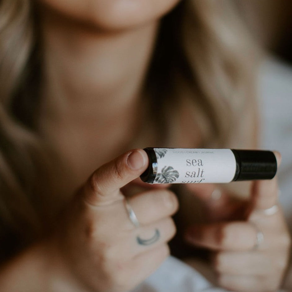 Sea Salt Surf roll-on perfume being held between women's fingers