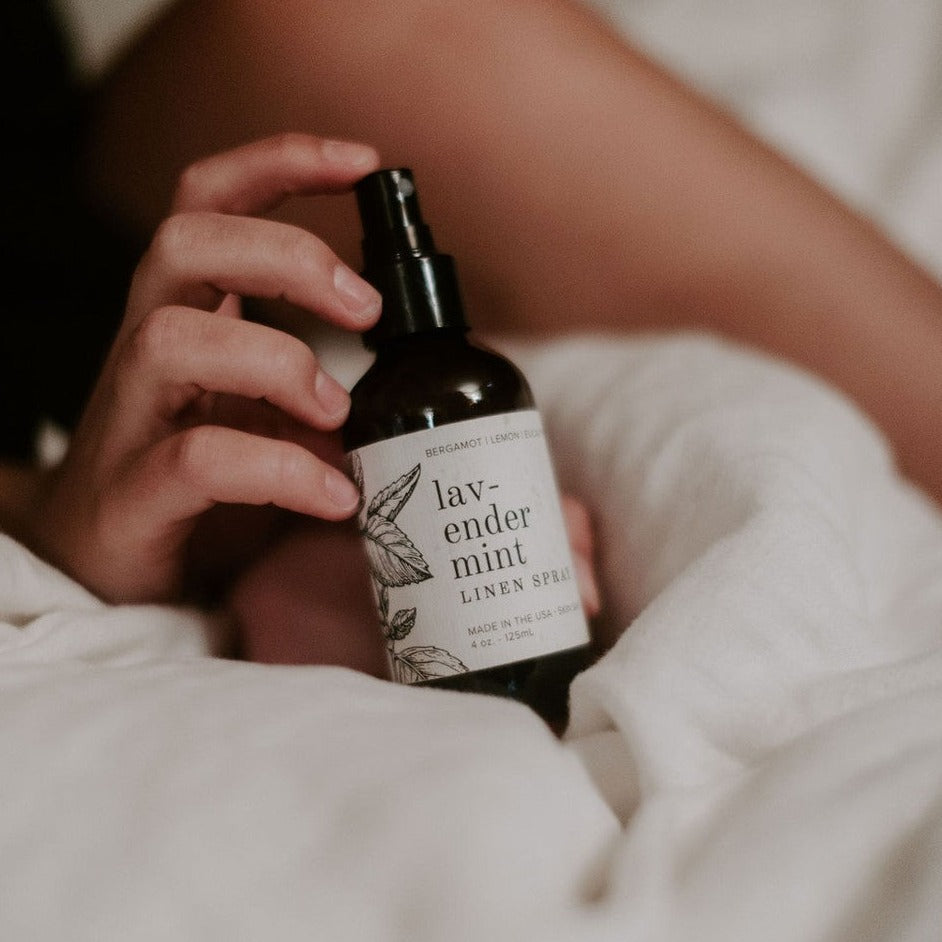 4oz Lavender Mint linen spray on bed being held by women's hand