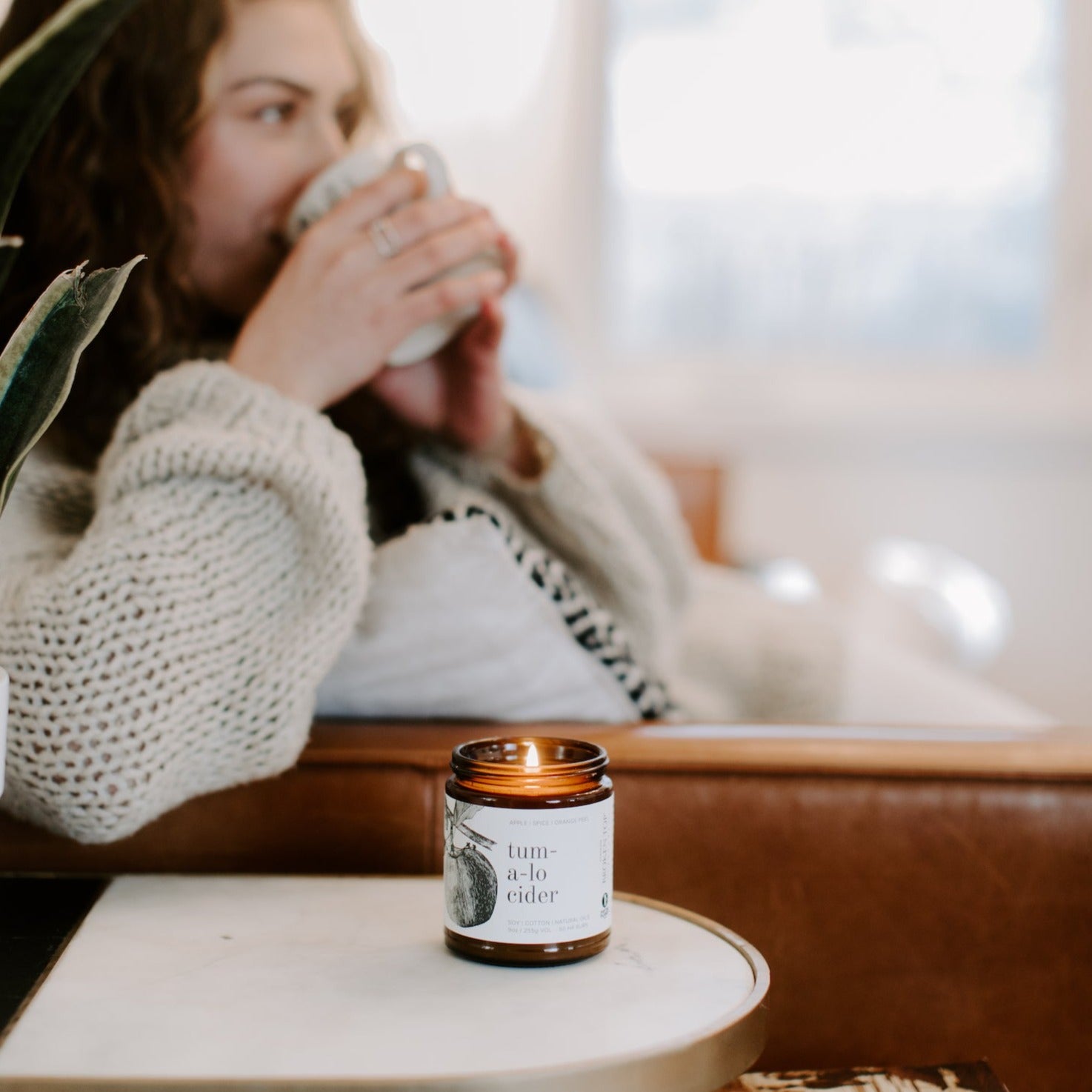 9oz Tumalo Cider candle side table with women drinking out of a cup