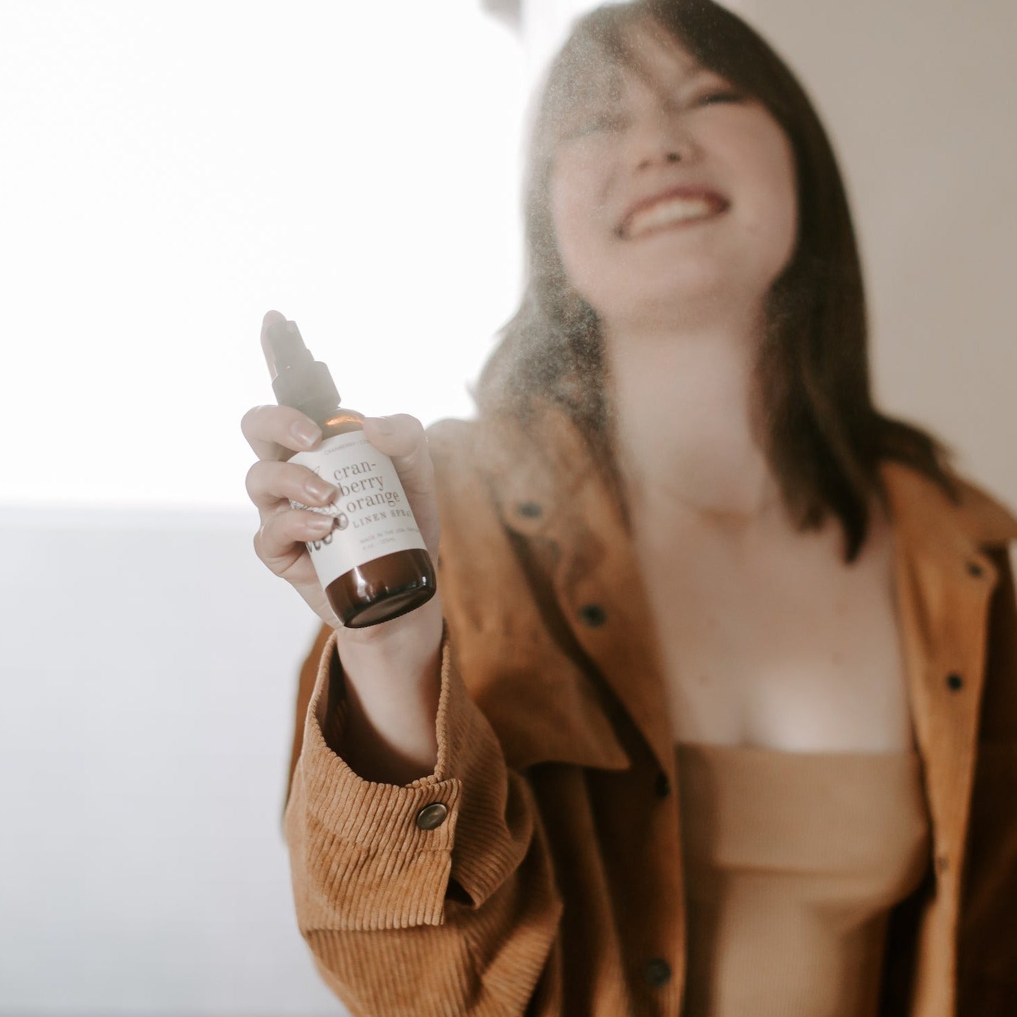 4oz Cranberry Orange linen spray being sprayed by smiling women