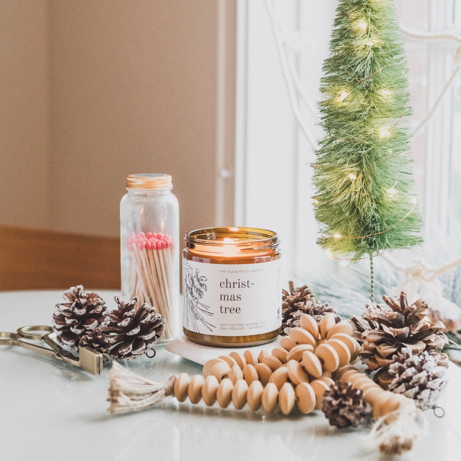 16oz Christmas Tree candle on glass table surrounded by holiday decor