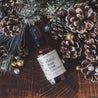 4oz Christmas Tree linen spray on wood table next to pinecones