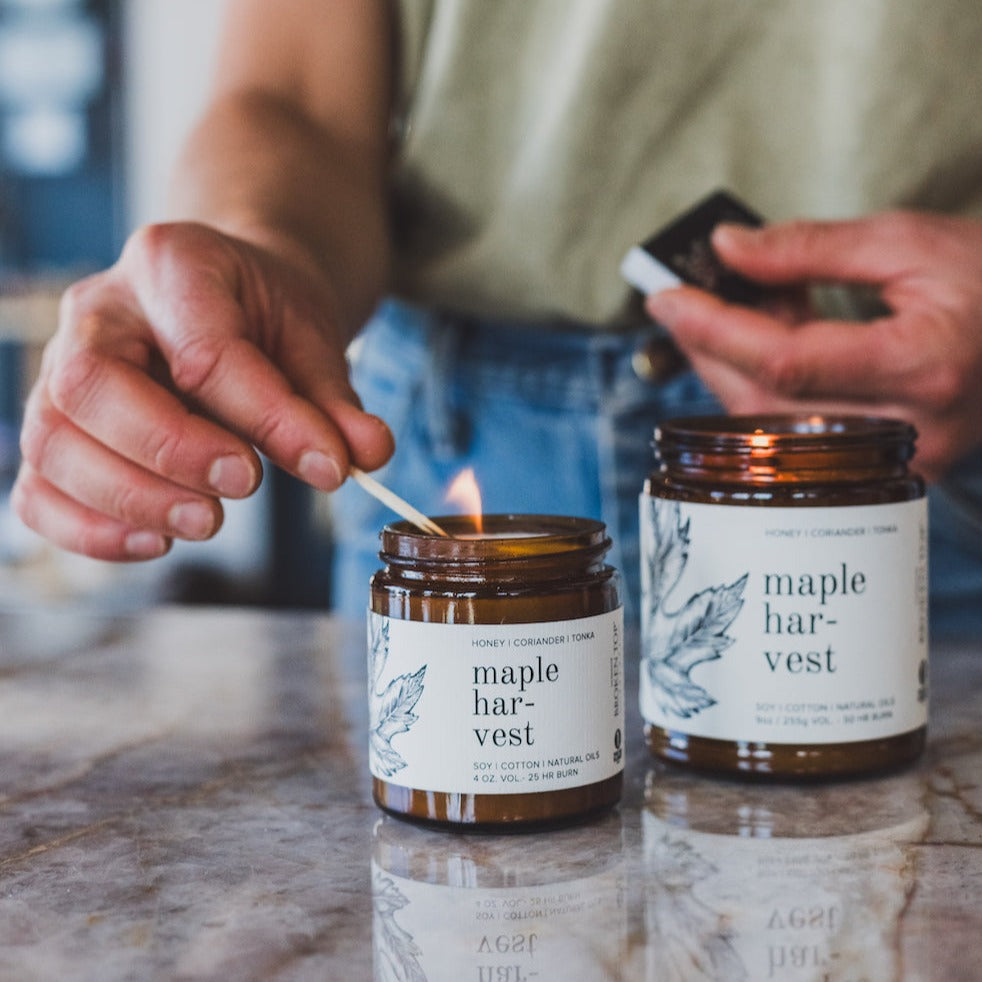 4oz Maple Harvest candle on kitchen counter and lit by wood match