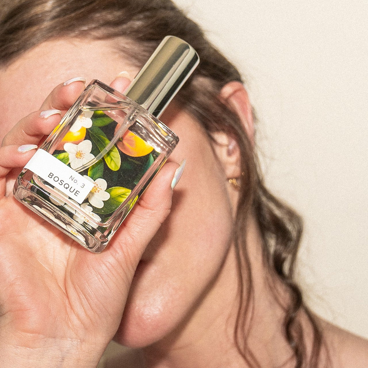Hand holding a floral perfume bottle with a blurred background