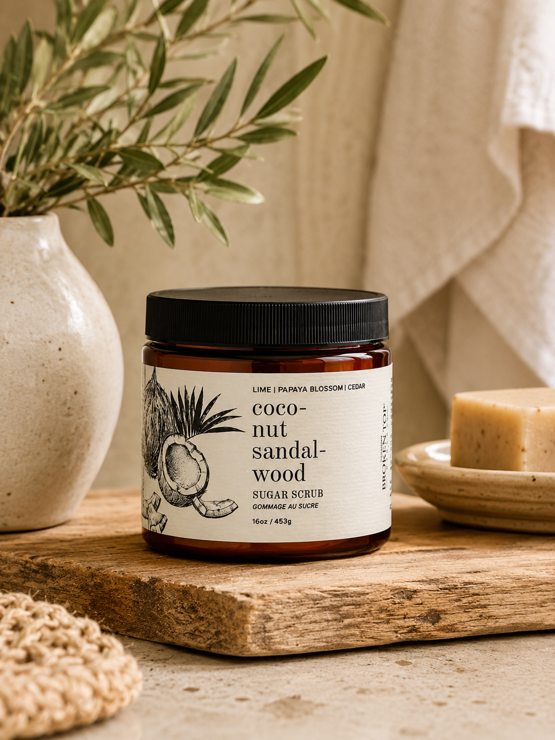 16oz Coconut Sandalwood Sugar Scrub on counter with plant in background