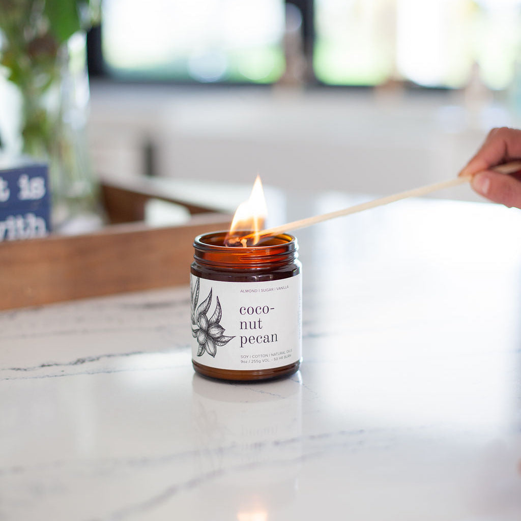 9oz Coconut Pecan Soy Candle being lit by a long match. 