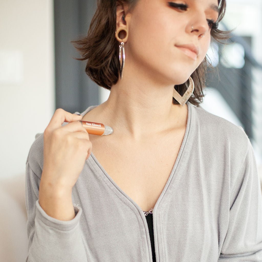 Young woman applying 'Sun Kissed' Roll On Perfume to neck