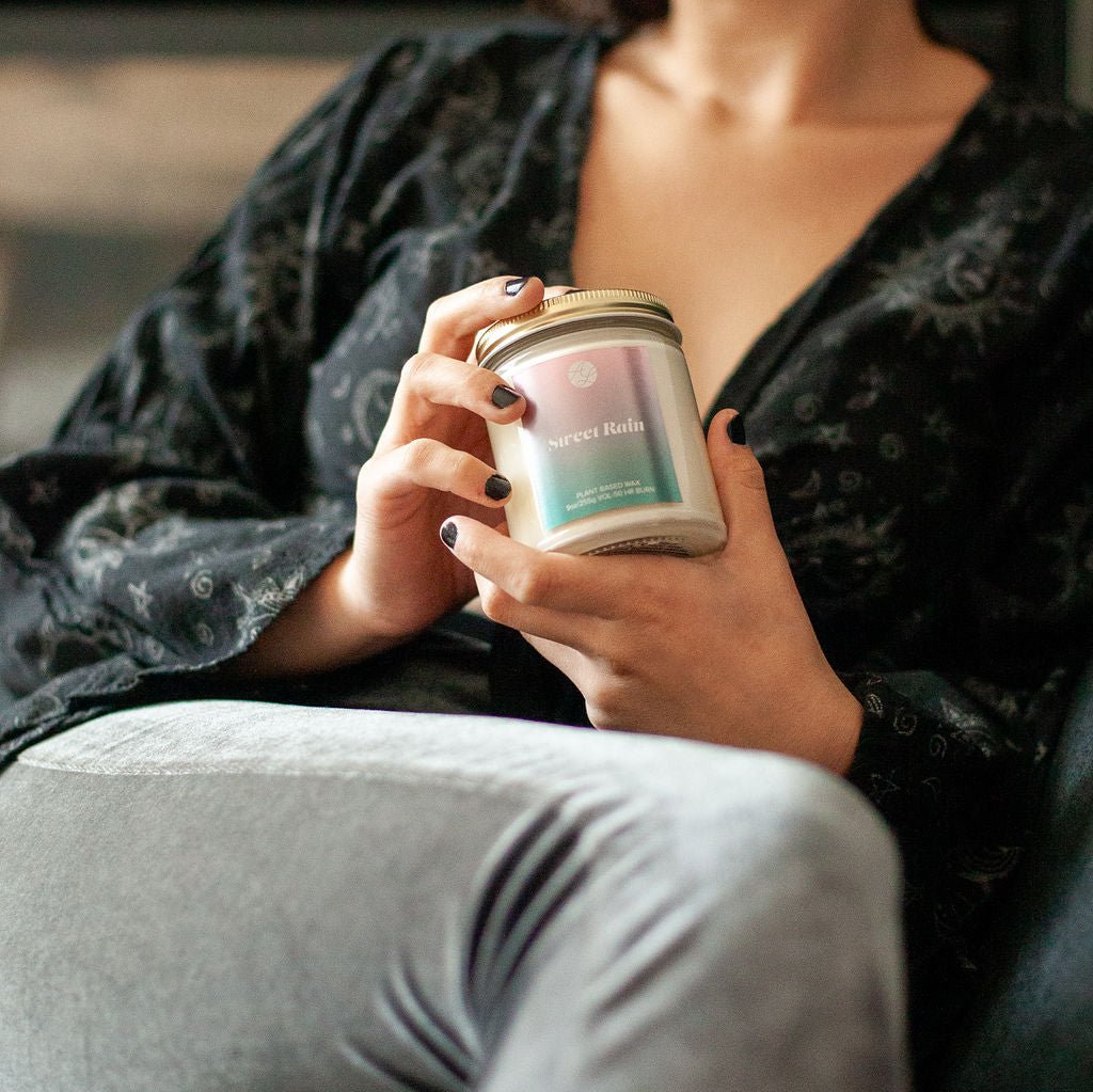 Young woman sitting, holding 9oz 'Sweet Rain' Soy Candle