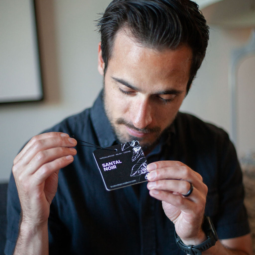 Santal Noir Car Freshener being held by a man. 