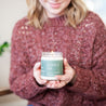 Young woman in red sweater holding a lit 9oz 'La Dolce Vita' Soy Candle