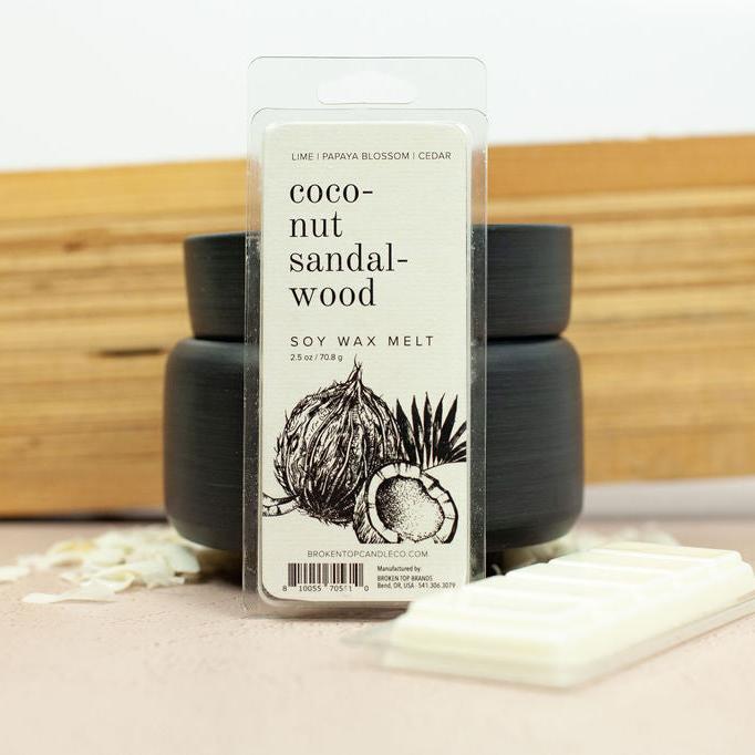 Coconut Sandalwood Wax Melts infront of black wax warmer next to coconut shavings