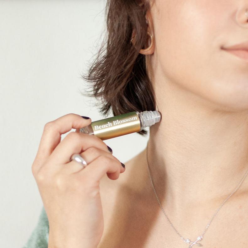 Young woman using 'Beach Blossom' 
Roll On Perfume on her neck