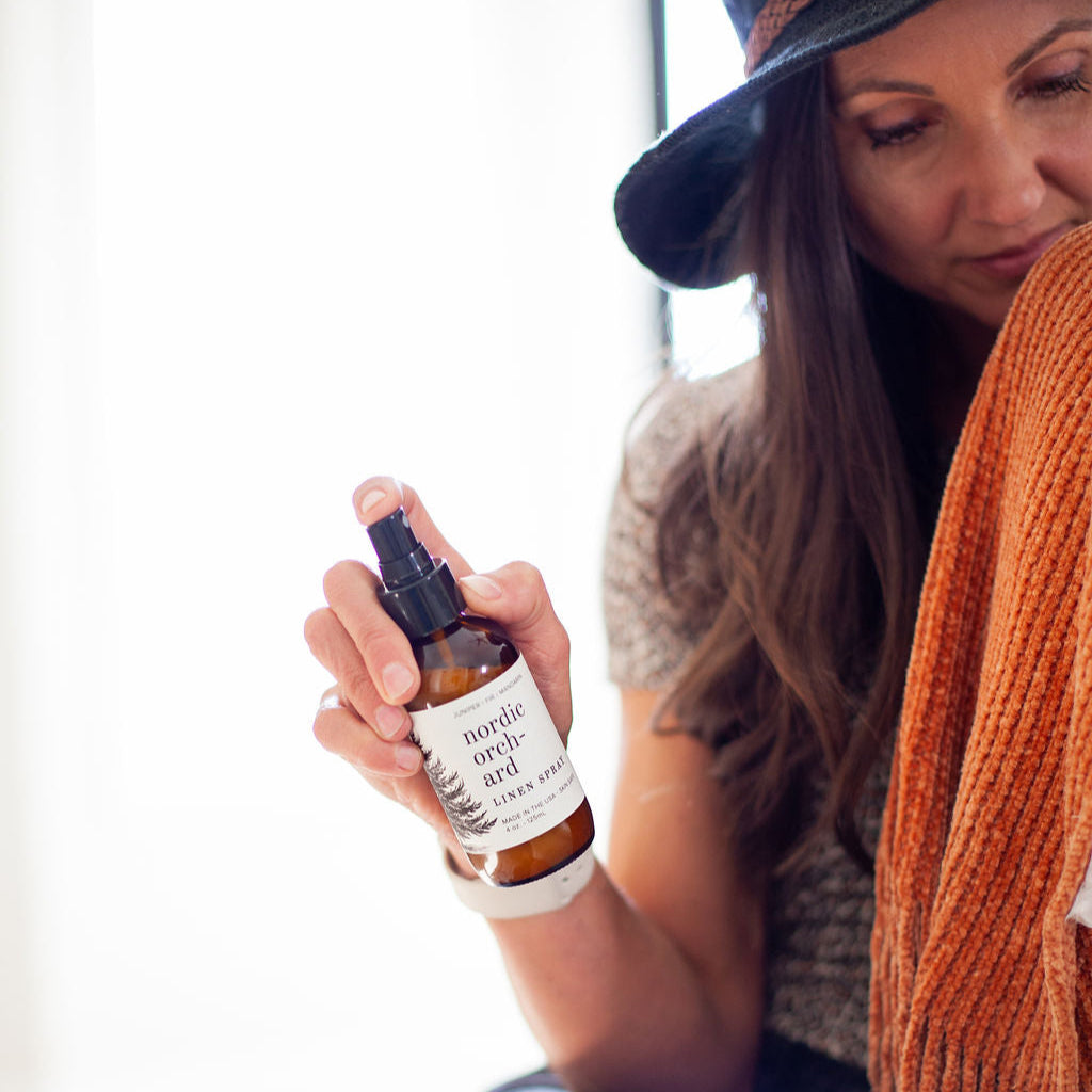 4oz Nordic Orchard Linen Spray being sprayed by a woman. 