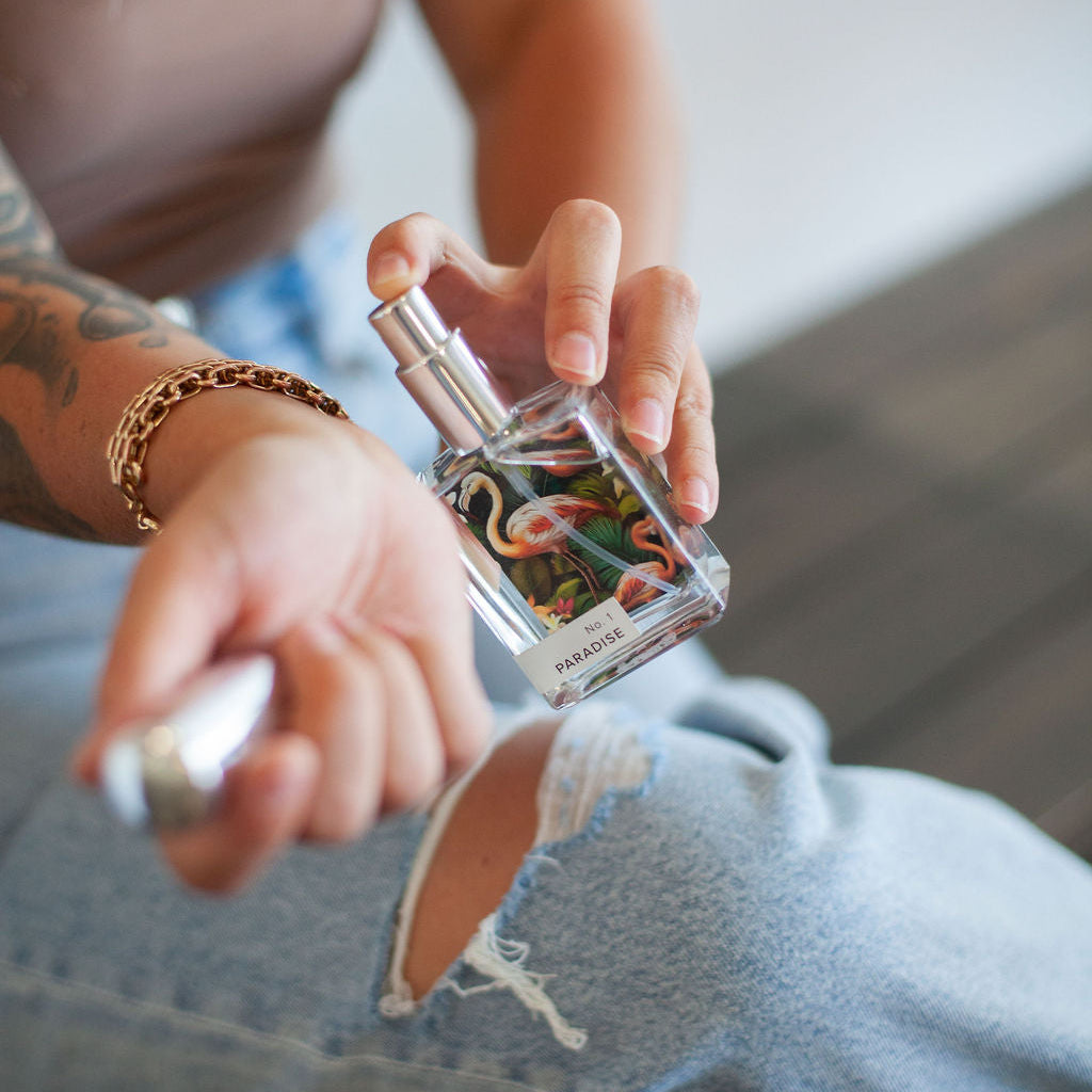 Person holding a small perfume bottle with a colorful label.