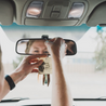 Sea Salt Surf Car Freshener being hung on a rearview mirror by two hands. 