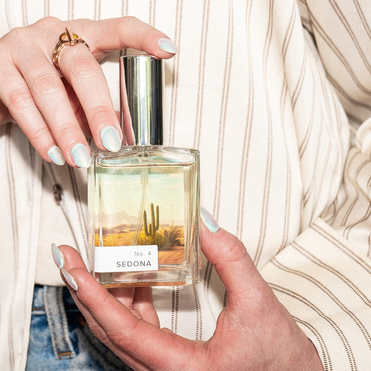 Person holding a perfume bottle labeled 'Sedona' with a scenic label.