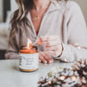 9oz Spiced Winter Plum candle being lit by women on white table