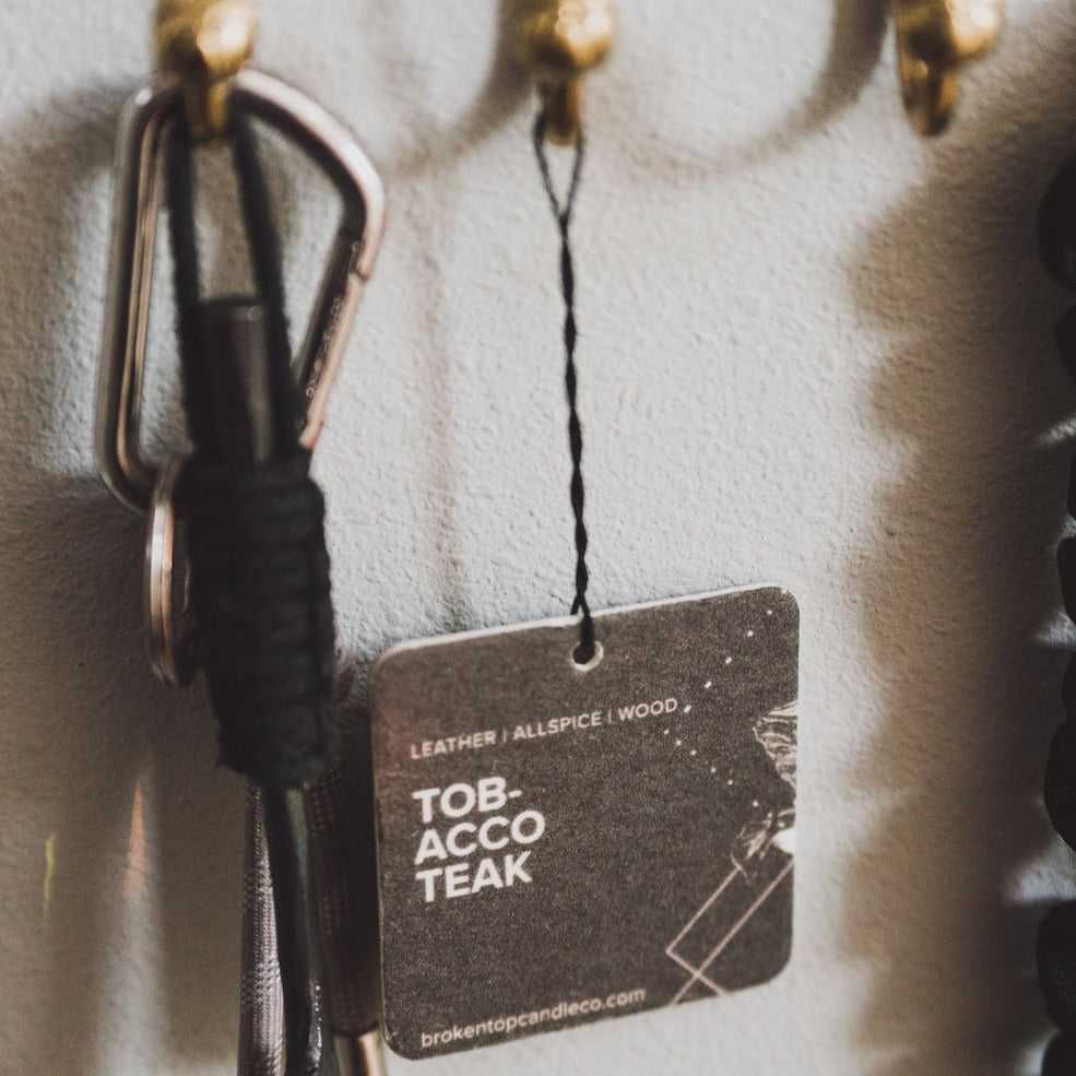 Tobacco Teak Car Freshener hanging on a hook. 