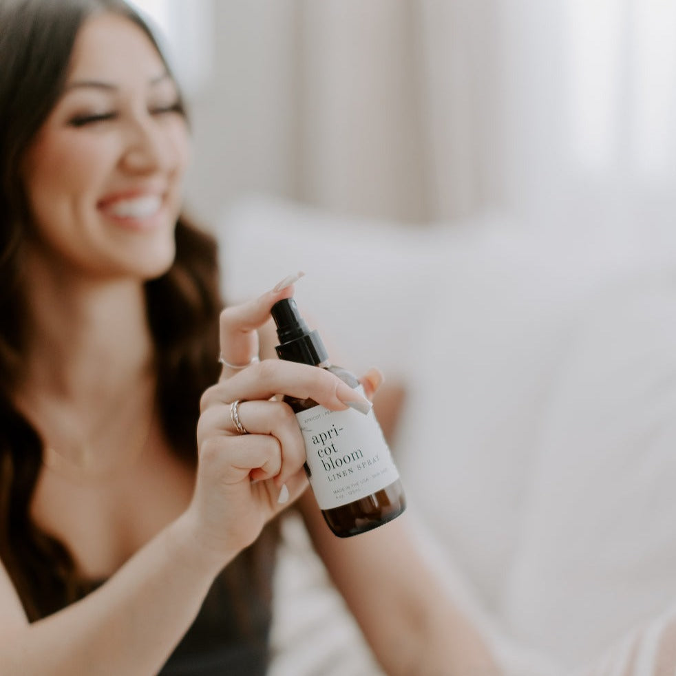 4oz Apricot Bloom linen spray being sprayed by smiling women