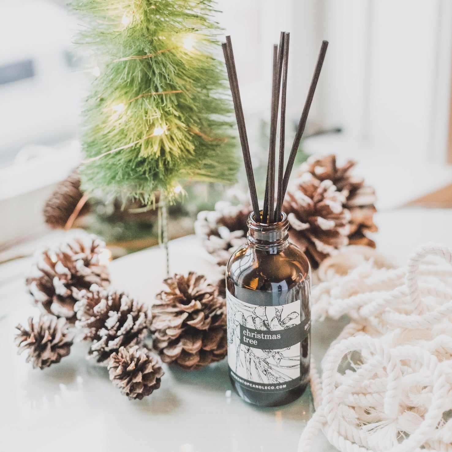 Christmas Tree Reed diffuser on table next to pinecones