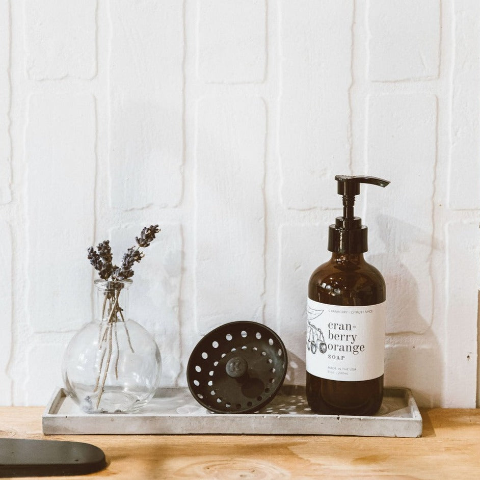 Coconut Sandalwood 8oz liquid soap on wood next to vase